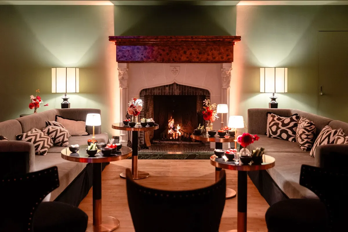 Salon du Barbizon illuminé par la cheminée pour une réception familiale en soirée