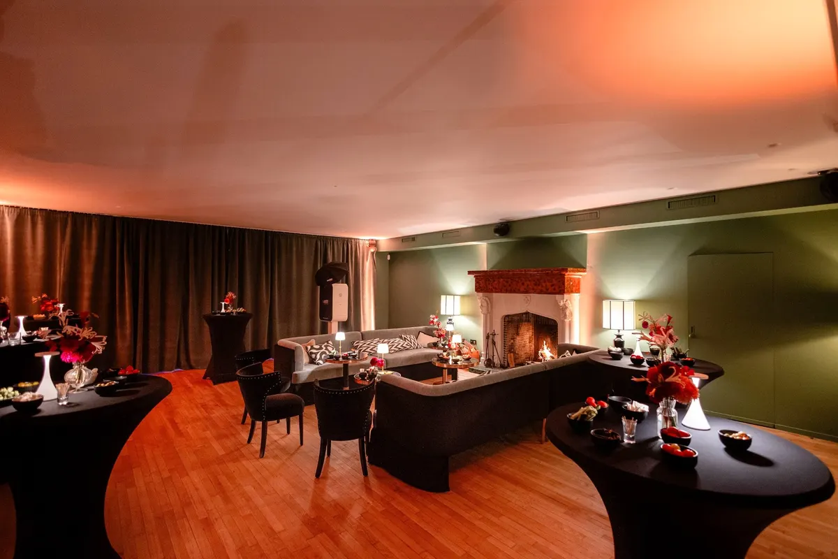 Vue d’ensemble du salon du Barbizon en soirée, avec cheminée allumée et tables de réception