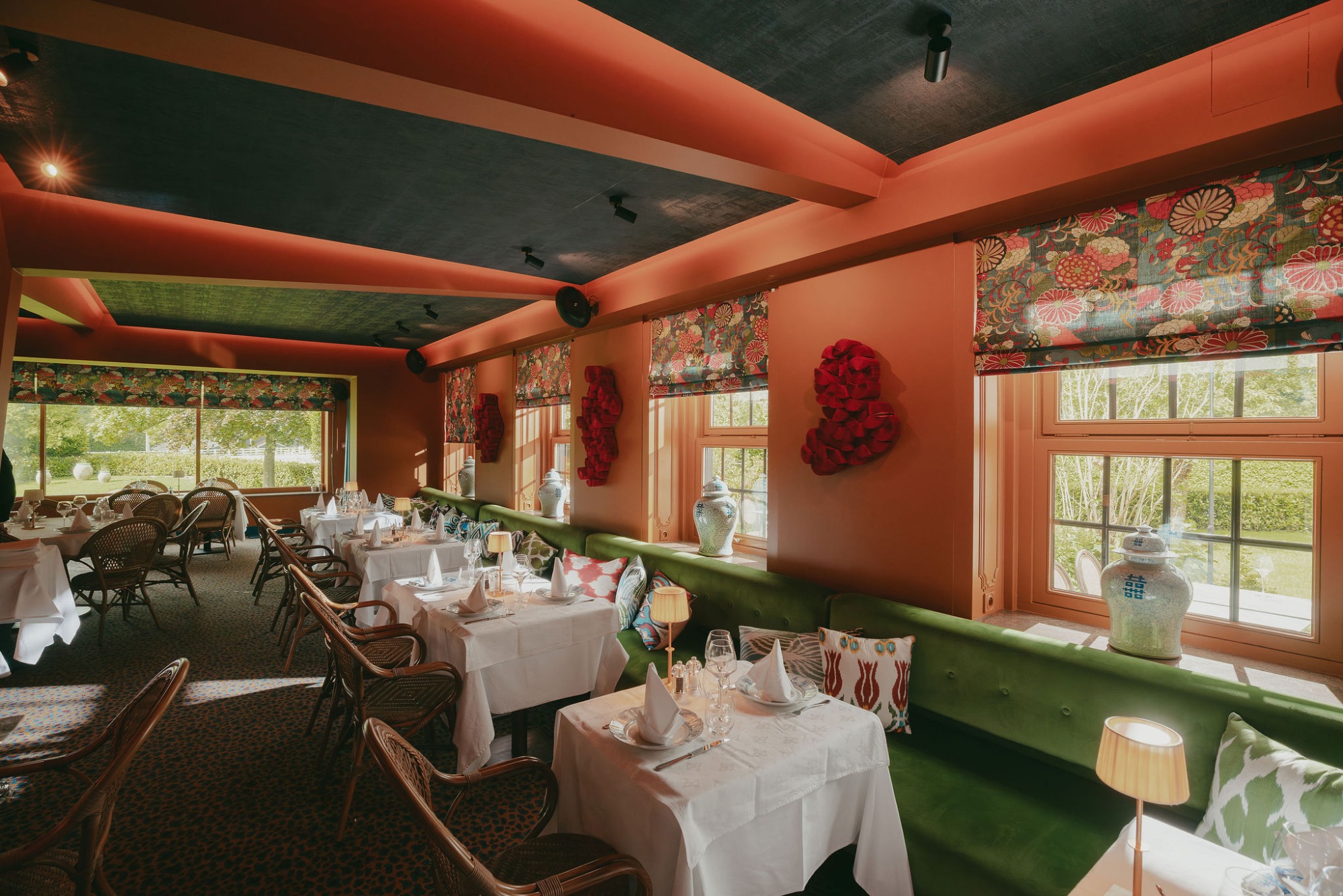 Salle orange du Barbizon, longue banquette en velours vert et tables nappées de blanc